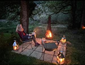 a woman sitting in a chair next to a fire at Luxus-Landhaus & Spa in Strachur