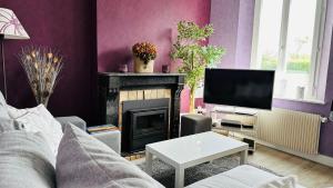 a living room with a fireplace and a tv at Maison Carpe HORAM proche de la mer in Cayeux-sur-Mer