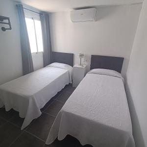 two beds in a small room with a window at Duquesa Harbour Club Aparthotel in Manilva