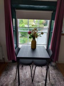 Streete retreat centre في ويستميث: مزهرية من الزهور تقف على طاولة أمام النافذة