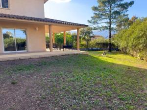 a house with a patio and a dog in the yard at 72 m2 Centre-ville avec jardin in Porto-Vecchio