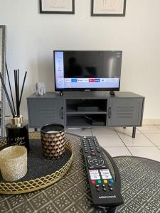 a living room with a tv and two remote controls at Le Sun Valley - Studio Cosy - Free Parking in Montpellier