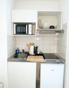 a white kitchen with a sink and a microwave at Le Sun Valley - Studio Cosy - Free Parking in Montpellier