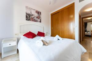 een slaapkamer met een groot wit bed met rode kussens bij CT 232 - Eden Golf Sur - Southfacing Apartment in Mijas