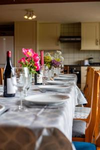 einen langen Tisch mit Tellern, Weingläsern und Blumen in der Unterkunft West Hollowcombe Farm in Dulverton