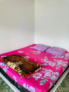 a bed with a pink blanket and pillows on it at Elsina guest house in Tuktuk Siadong