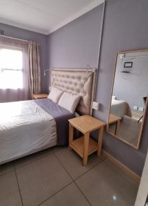 a small bedroom with a bed and a mirror at Matat Studio Apartments in Matatiele
