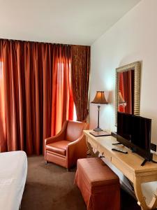Habitación de hotel con escritorio, TV y silla en Mainalon Resort, en Tripolis