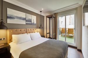 a bedroom with a large bed and a balcony at Hotel Cortes Rambla in Barcelona