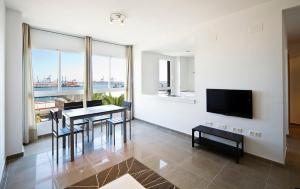 uma sala de estar com uma mesa e cadeiras e uma televisão em Apartamentos Marina Suites em Grao de Castellón