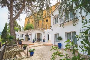 a white house with a tree and stairs at Hotel Boutique Palacio De La Duquesa in Ronda