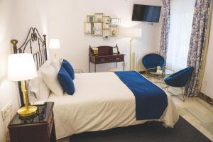 Hotel Boutique Palacio De La Duquesa في روندا: غرفة نوم بسرير كبير وكراسي زرقاء