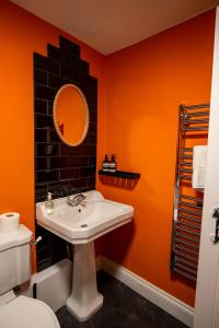 an orange bathroom with a sink and a mirror at West Hollowcombe Farm in Dulverton