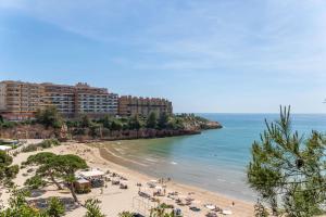una spiaggia con un gruppo di persone e l'oceano di TuristMar - Amplio Apartamento en Salou con piscina, a 2 minutos de la Playa a Salou