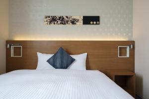 uma cama com lençóis brancos e almofadas azuis em Hotel Vista Nagoya Nishiki em Nagoia