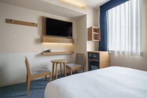 名古屋的住宿－名古屋錦酒店，酒店客房配有1张床、2把椅子和电视。