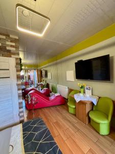 a living room with green and pink furniture and a flat screen tv at Apartament "Love Island" z Jacuzzi SPA dla Dwojga in Gniezno
