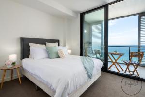um quarto com uma cama grande e uma varanda em Beachfront Beauty - Wifi Included em Newcastle