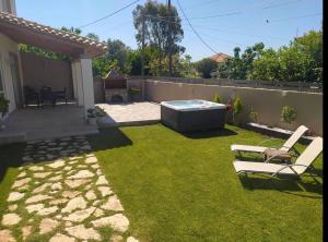 a backyard with a hot tub and two lawn chairs at Villa Tesoro in Agios Georgios