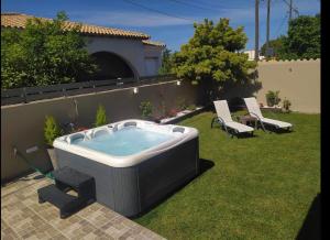 a hot tub in a yard with two chairs at Villa Tesoro in Agios Georgios