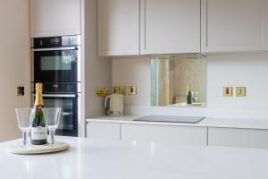 a white kitchen with a bottle of champagne and glasses at GuestReady - Amazing house in Sandymount in Dublin +39 photos