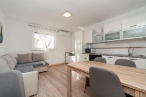 a kitchen and living room with a table and a couch at Ema's Olive Garden Apt 1 with private parking, just 10 minutes drive from sandy beach in Poličnik