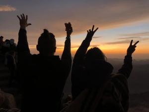 达哈布Tranquilo Boutique Hostel - Dahab的一群人站在山顶上，举起双手