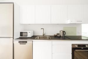 a white kitchen with a sink and a microwave at Fantastic 2-bed apartment with balcony in Odense