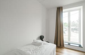 a white bedroom with a bed and a window at Fantastic 2-bed apartment with balcony in Odense