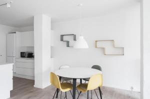 a white kitchen with a white table and yellow chairs at Fantastic 1-bed apartment w private terrace in Aarhus