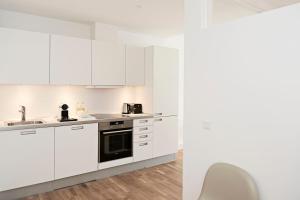 a white kitchen with white cabinets and a sink at Cool 1-bed with private terrace in Copenhagen
