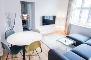 Beautiful 2-bed in great location في أُرهوس: غرفة معيشة مع طاولة بيضاء وكراسي زرقاء