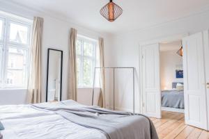 Beautiful 2-bed in great location في أُرهوس: غرفة نوم بيضاء مع سرير ومرآة