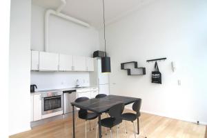 Cool 1-bed in fantastic Østerbro location في كوبنهاغن: مطبخ أبيض مع طاولة سوداء وكراسي