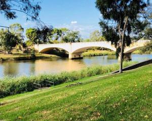 a bridge over a river next to a grass field at South Yarra Urban Haven in Melbourne