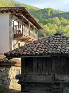 uma casa antiga com um telhado de azulejo e uma varanda em La Balconada de Valdeón em Posada de Valdeón