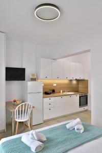 a kitchen with white cabinets and a table and a chair at Centro Apartments by Comfortbnb- Sitia in Sitia
