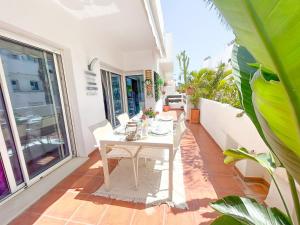 een witte tafel en stoelen op een balkon met planten bij Apartamento Golf Valle Romano in Estepona