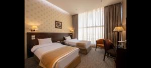 een hotelkamer met twee bedden en een stoel bij Lotus Hotel in Amman