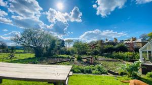 un banco en un jardín bajo un cielo azul en Beachborough Country House en Barnstaple