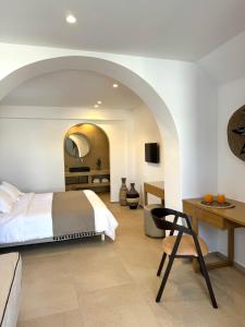 a bedroom with a bed and a table and a desk at Esperides in Platis Yialos Mykonos
