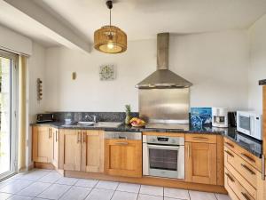 eine Küche mit Holzschränken und einem Herd mit Backofen in der Unterkunft Holiday Home Port Morvan by Interhome in Planguenoual