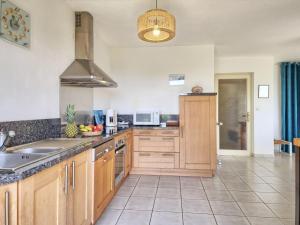 eine große Küche mit Holzschränken und einem Waschbecken in der Unterkunft Holiday Home Port Morvan by Interhome in Planguenoual