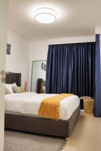 a bedroom with a large bed with blue curtains at Astoria Apartments Lovely One Bedroom Apartment With AC & UPS in Lavington in Nairobi +35 photos