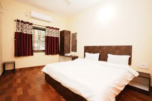 Un dormitorio con una gran cama blanca y una ventana en Springfield Family Apartment en Mahabaleshwar