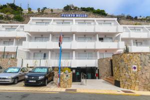 a building with two cars parked in front of it at Apartamentos LIVVO Puerto Bello in Puerto Rico de Gran Canaria