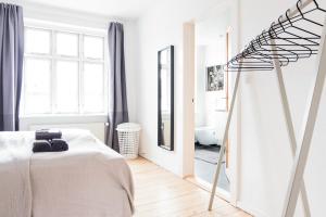 Habitación blanca con cama y espejo en Spacious and cool 1-bed in Øgadekvarteret en Aarhus