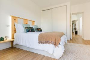 a bedroom with a large white bed with a wooden headboard at Casa Ti'Rosa in Caniço