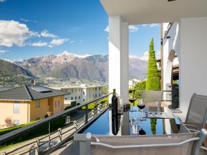 - un balcon avec une table, des verres à vin et des montagnes dans l'établissement Apartment Residence Miralago - Utoring Apt- D32 by Interhome, à Piazzogna