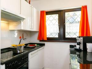 - une cuisine avec des placards blancs et des rideaux orange dans l'établissement Apartment Residence Miralago - Utoring Apt- D32 by Interhome, à Piazzogna